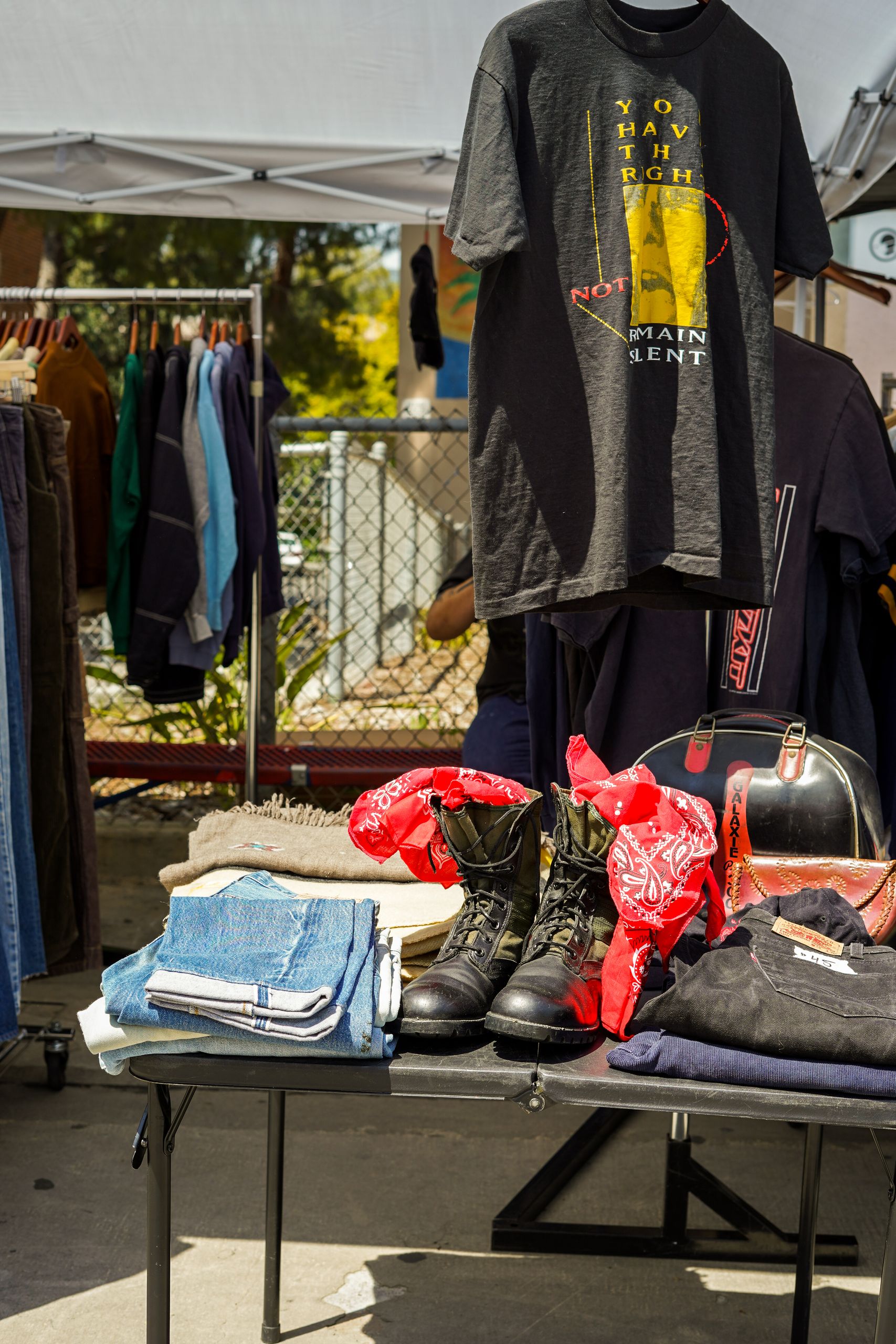 Display of vintage clothes and accessories at an outdoor market on a sunny day.